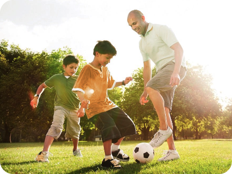 Padre jugando al fútbol con sus dos hijos en una tarde soleada